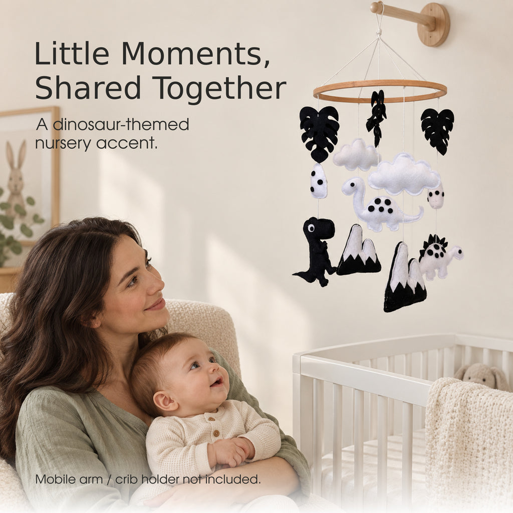 Mother and baby looking at a black and white dinosaur baby mobile