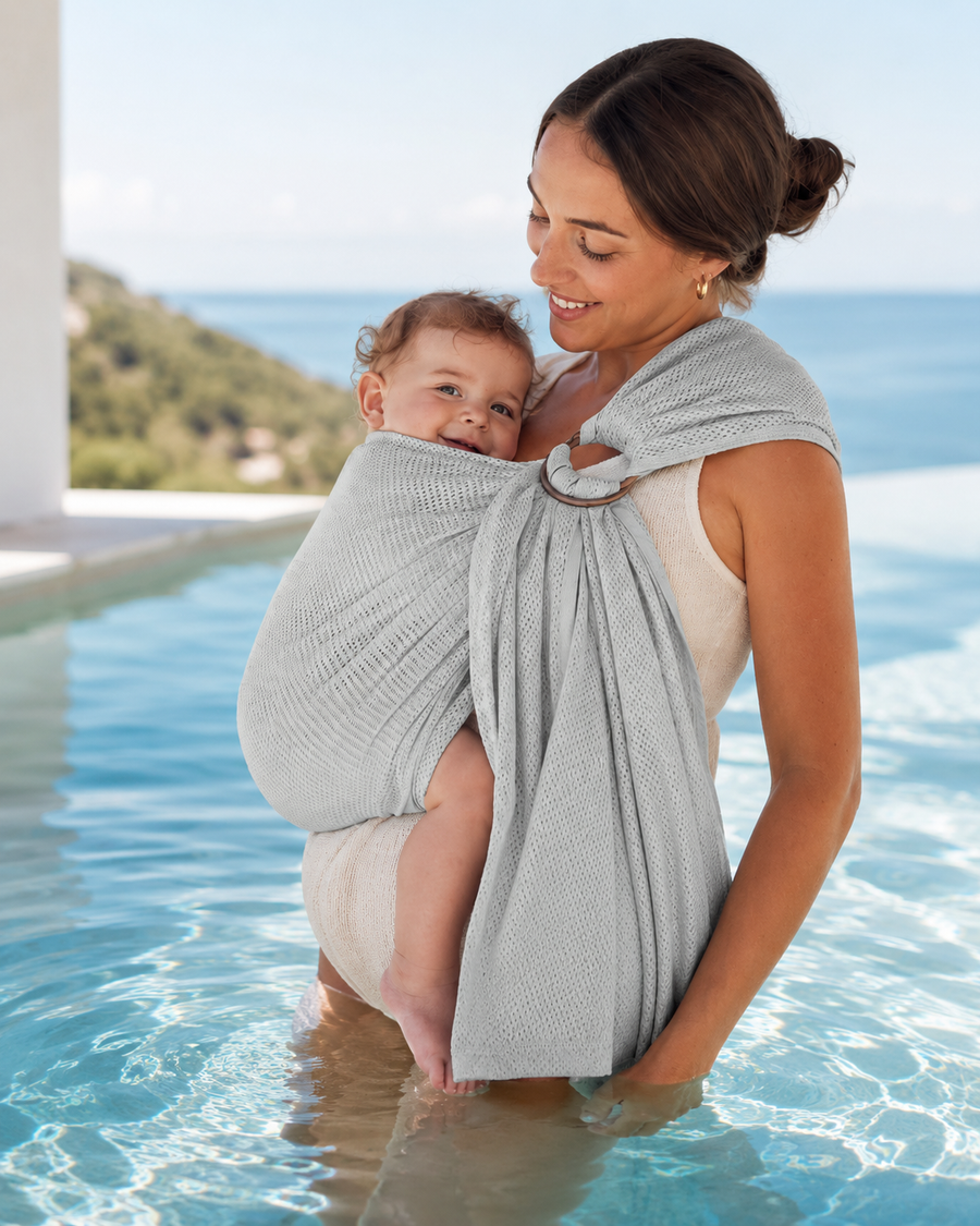 Parent carrying baby in a water ring sling in a pool